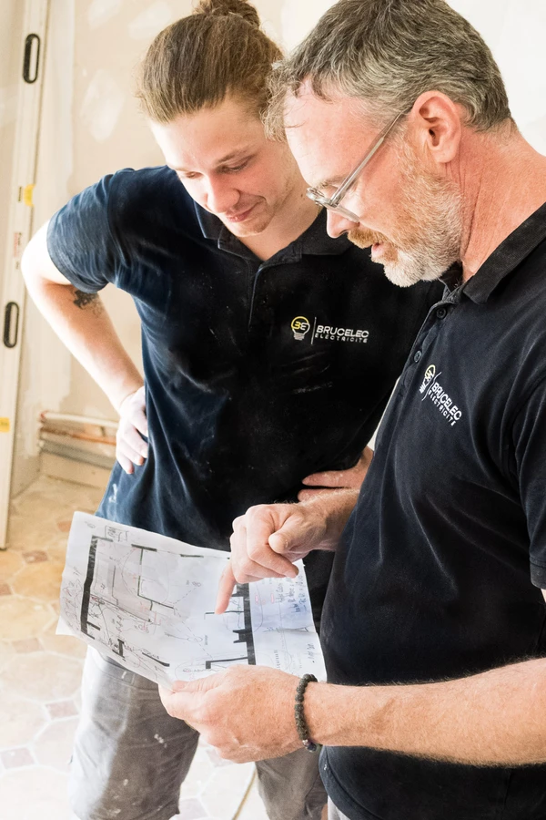 Électriciens BRUCELEC étudiant un plan de chantier
